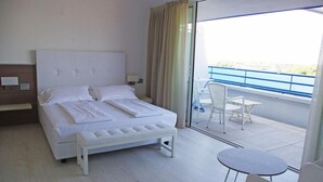 A hotel room with a bed, a small table, and a balcony with chairs.