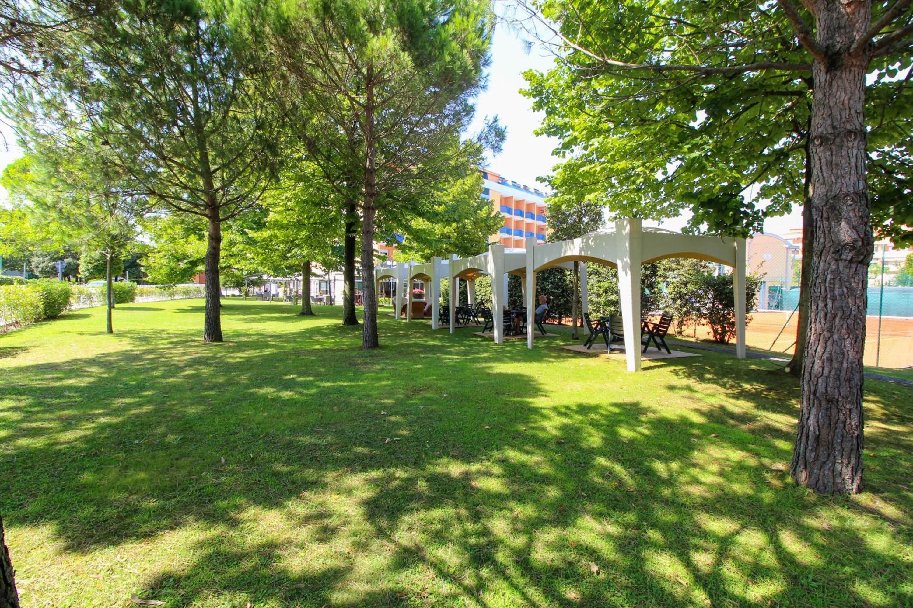 A park with trees, a gazebo, and a building in the background.