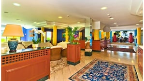 A spacious lobby with a reception desk, seating area, and decorative plants.