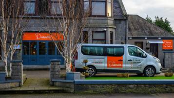 Un fourgon blanc était garé devant un immeuble dont la porte était bleue et qui affichait une enseigne orange sur laquelle on pouvait lire « Dunavon ».