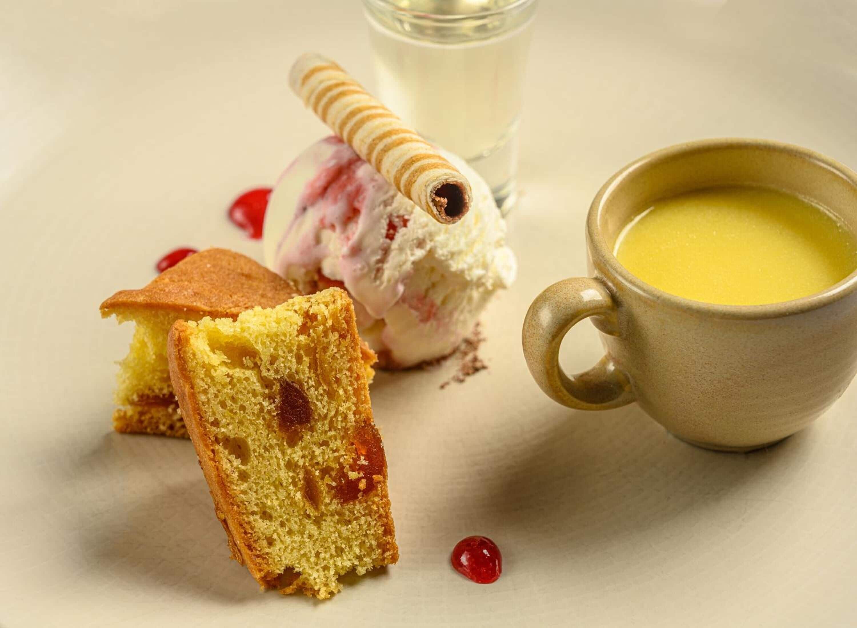 Una rebanada de pastel, una bola de helado y una taza de té sobre una mesa.