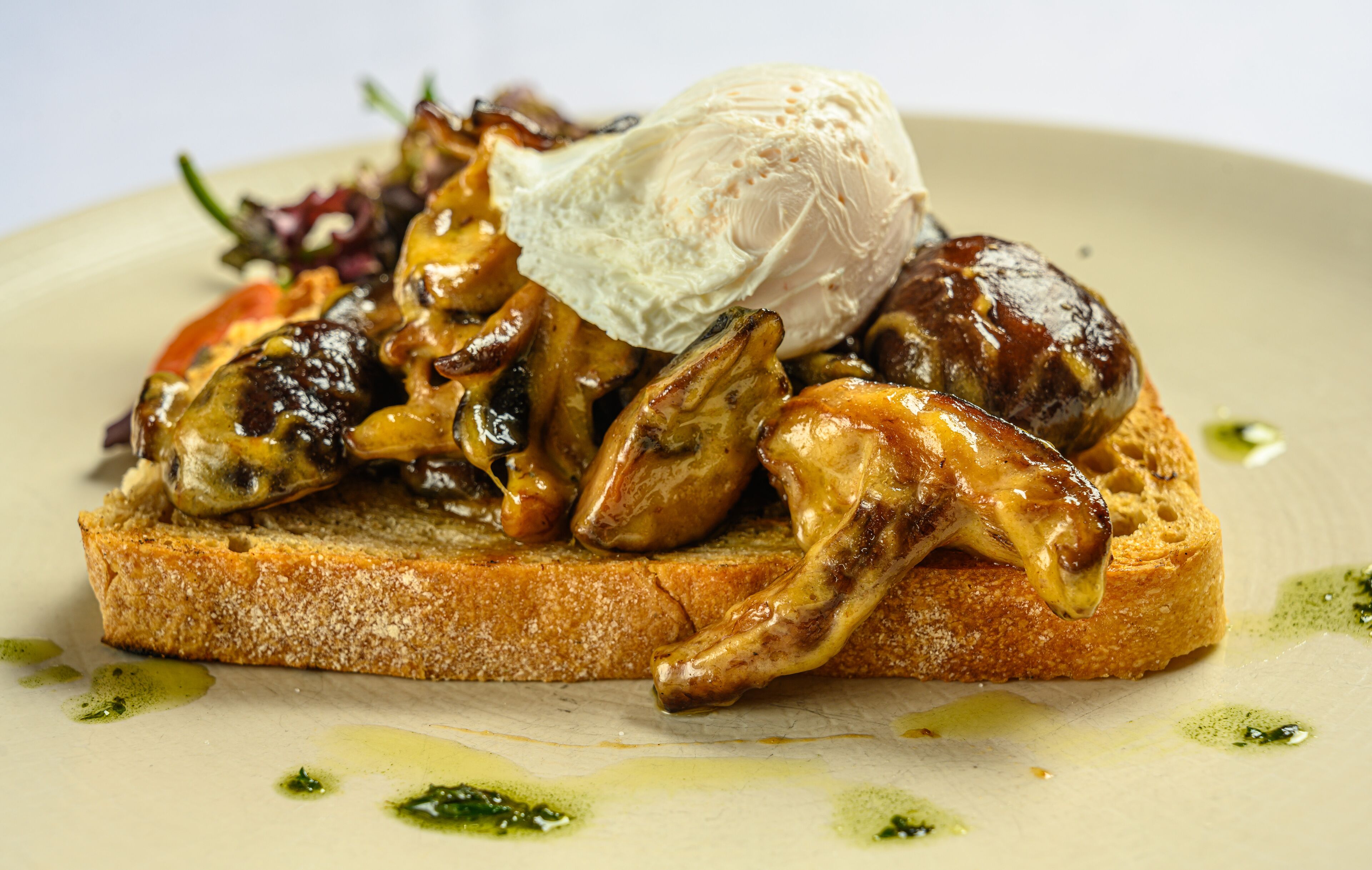 A dish with grilled mushrooms on toast, a scoop of ice cream, and a green sauce.