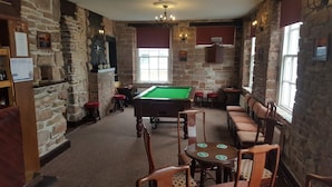 A billiards room with a pool table, chairs, and a bar area with stools. - Ecclefechan Hotel (Lockerbie)