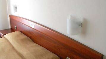Habitación de hotel con cama, mesita de noche con teléfono, lámpara de pared y un cuadro en la pared.