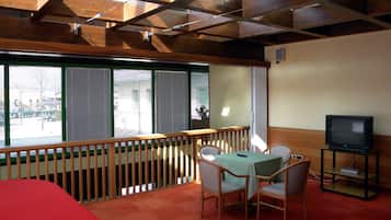 Ein Zimmer mit Balkon, Fernseher, Tisch und Stühlen sowie einem Bett.