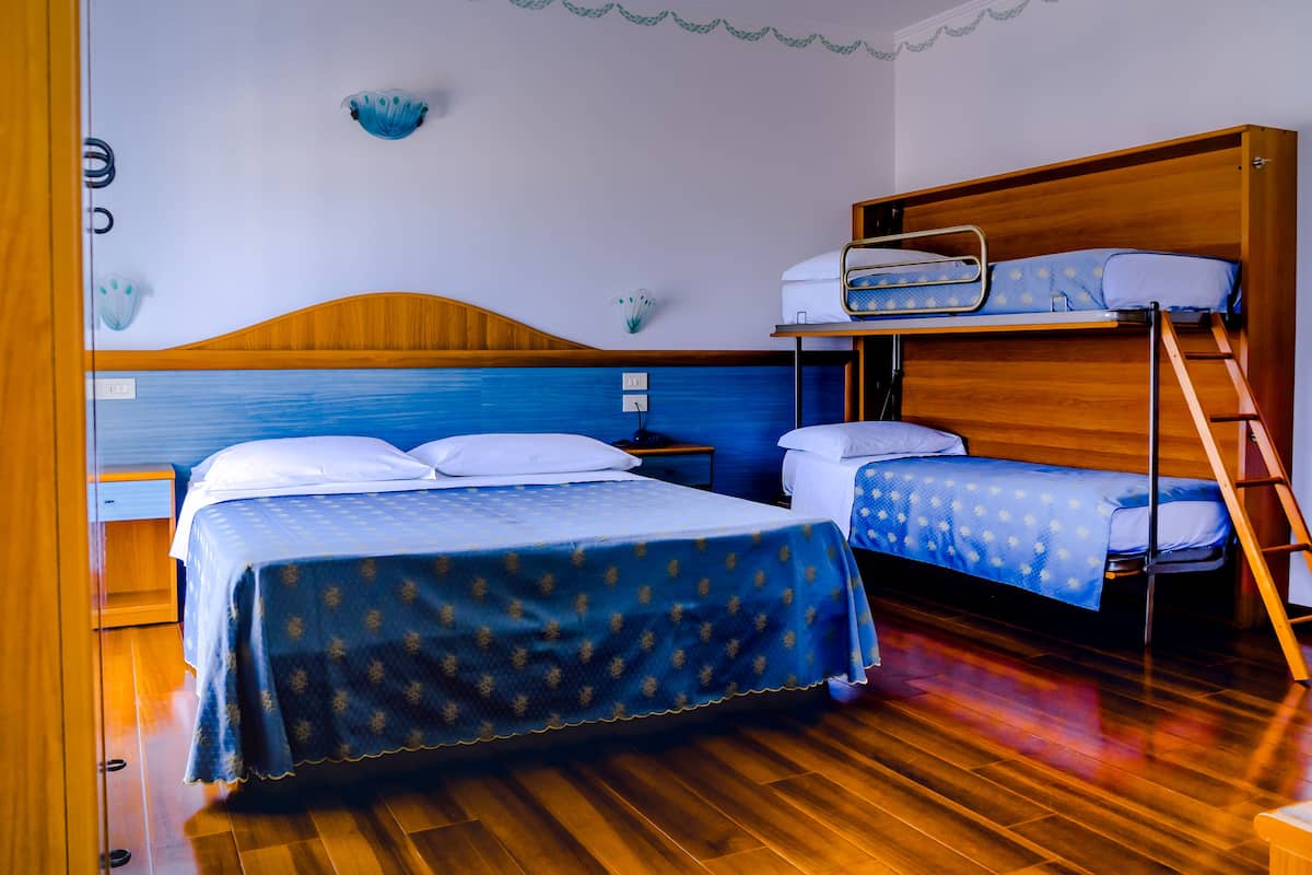 Une chambre avec deux lits, un lit superposé en bois, une échelle et une petite table.
