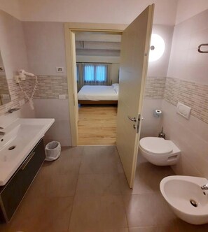 A hotel bathroom with a sink, toilet, and shower area. - Hotel Calinferno (Codogne)