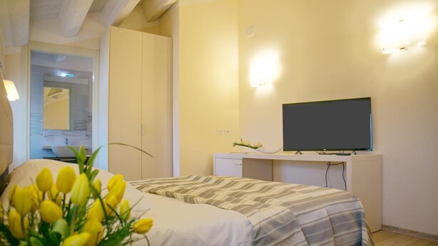 A bedroom with a bed, a desk with a flat-screen TV, and a mirror.