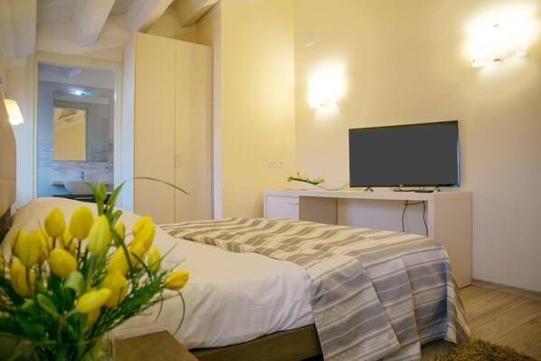 A bedroom with a bed, a desk with a flat-screen TV, and a mirror.
