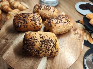 A wooden board with pastries, including croissants and chocolate-topped pastries.
