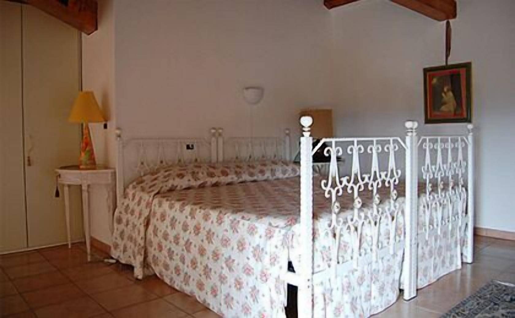 Ein Schlafzimmer mit einem Bett, einem Nachttisch, einer Lampe und einem Bild an der Wand.