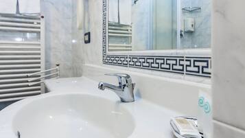 A bathroom with a white sink, chrome faucet, and a mirror with a decorative border.