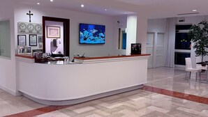 A reception desk with a clock, framed certificates, and a digital screen displaying a map. - Hotel Venice (Grisignano di Zocco)