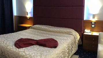 Ein Hotelzimmer mit einem großen Bett, einem Kopfteil, zwei Nachttischen inklusive Lampen und einem kleinen Beistelltisch.