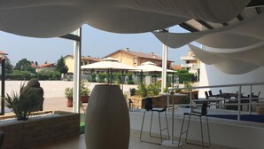An outdoor dining area with a large vase centerpiece, outdoor seating, and a view of the surrounding neighborhood. - Hotel Venice (Grisignano di Zocco)