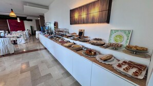 A buffet setup with various food items and a wall-mounted light fixture. - Hotel Venice (Grisignano di Zocco)