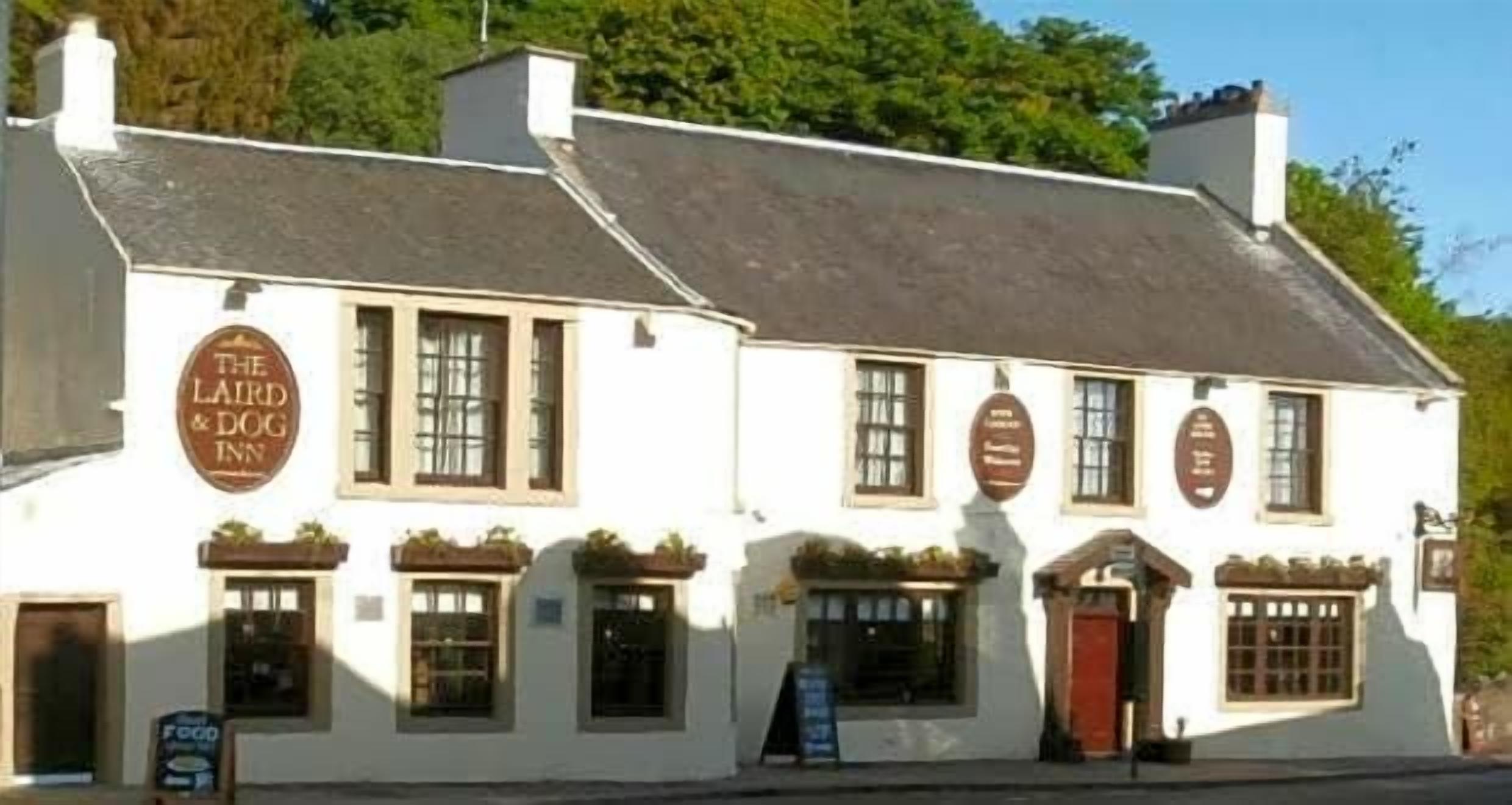 Un edificio tradizionale bianco con un cartello che riporta la scritta 'The Laird & Dog Inn'.
