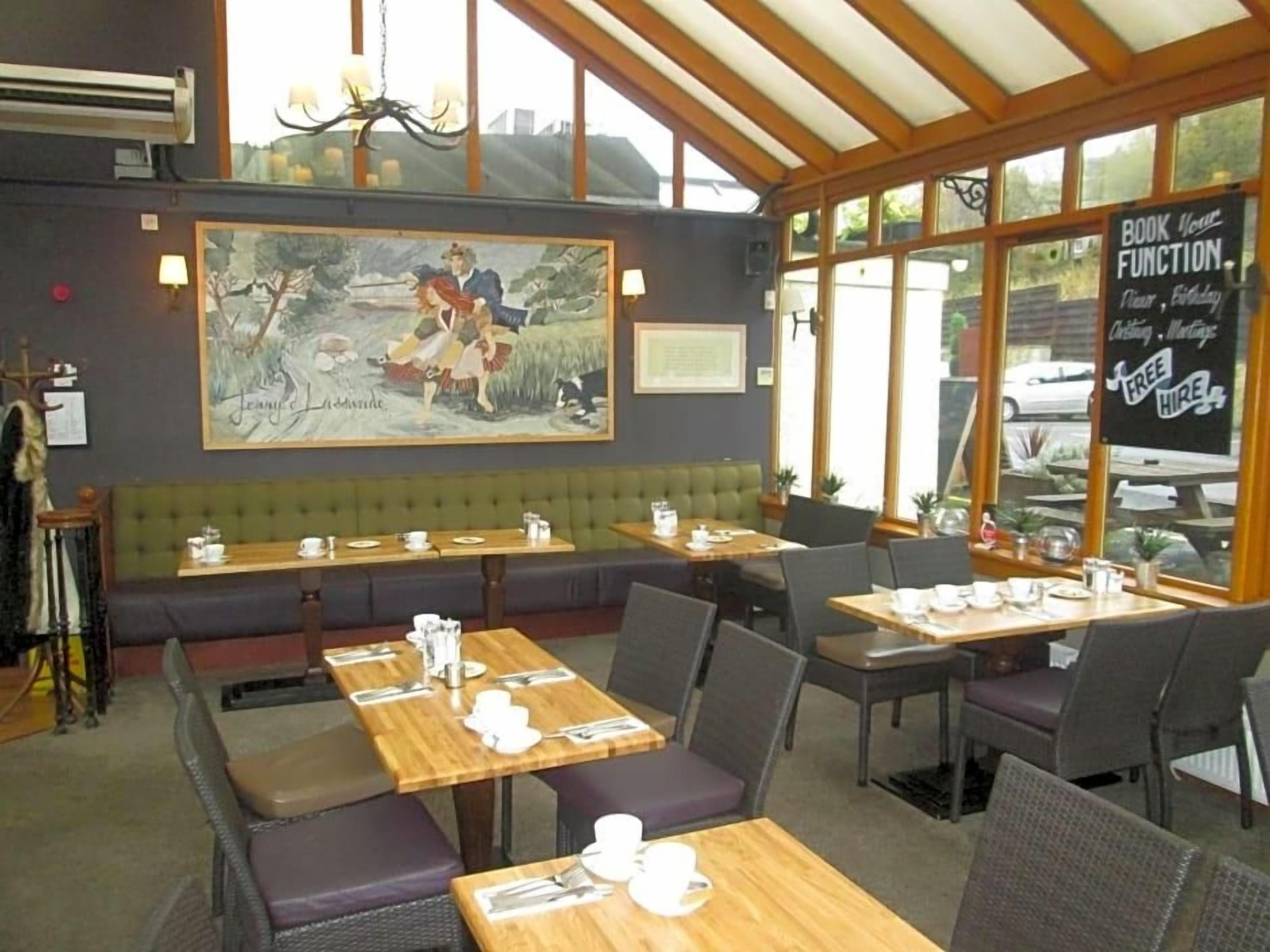 A restaurant with booths and tables, a mural on the wall, and a sign for booking functions.