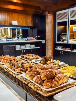 Un bufé con diversas opciones de panadería, incluyendo croissants y muffins.