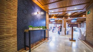 A lobby with a reception desk, a patterned wall, and a seating area with tables and chairs. - Apartamentos Torreluz (Almeria)
