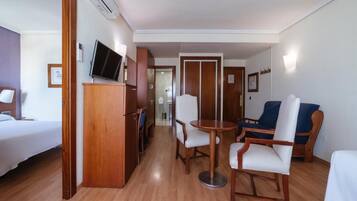 Ein Hotelzimmer mit einem Bett, einem Fernseher, einem Esstisch mit Stühlen und einem Sofa.