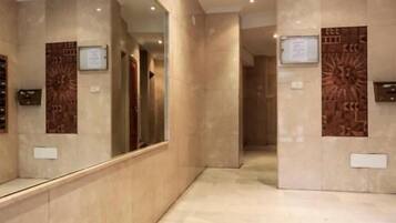 A corridor with a reflective wall and a patterned wall, leading to a door.