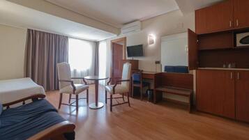 Habitación de hotel con cama, escritorio, silla, televisor y armario.
