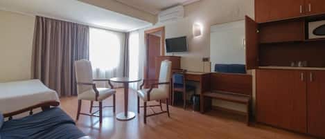 A hotel room with a bed, a desk, a chair, a television, and a wardrobe.
