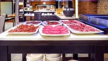Mesa de buffet com diversos pratos de carne.