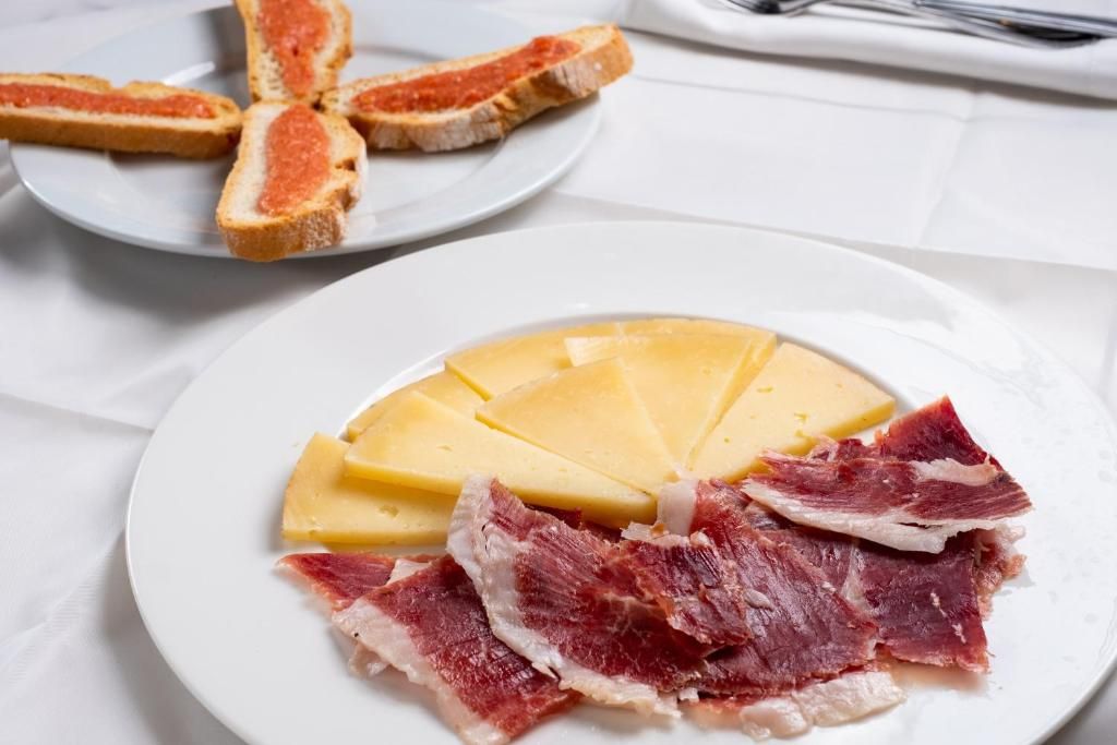 Un plato con queso y embutidos.