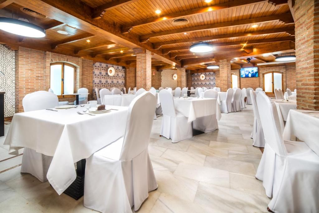 A banquet hall with multiple round tables, white tablecloths, and matching chairs.