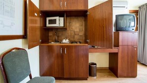 A compact kitchenette with a microwave, a small sink, and a television. - Apartamentos Torreluz (Almeria)