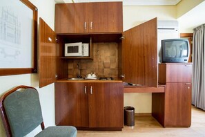 A compact kitchenette with a microwave, a small sink, and a television. - Apartamentos Torreluz (Almeria)