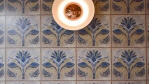 A dining table set with plates, cutlery, and a candle, against a tiled wall with a floral pattern. - Apartamentos Torreluz (Almeria)