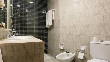 A modern bathroom with a marble sink, a bidet, and a toilet.