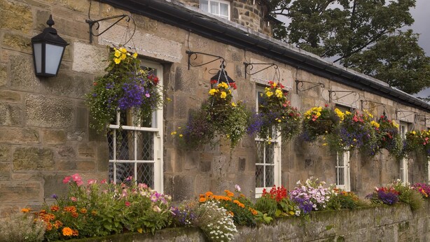 A stone building with hanging flower baskets and a lantern. - Premier Inn Edinburgh East (Edinburgh)
