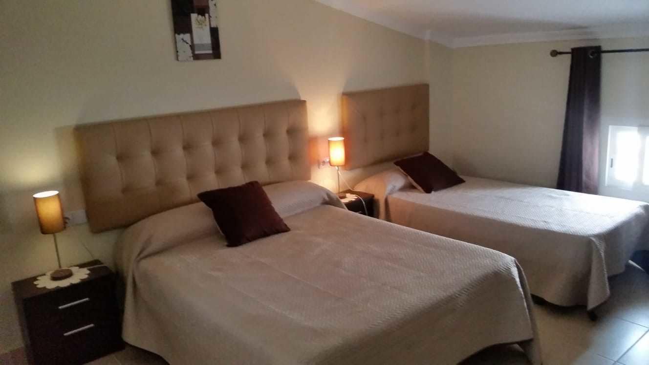 Ein Hotelzimmer mit zwei Betten, jeweils mit Kopfteil und Nachttischlampen.