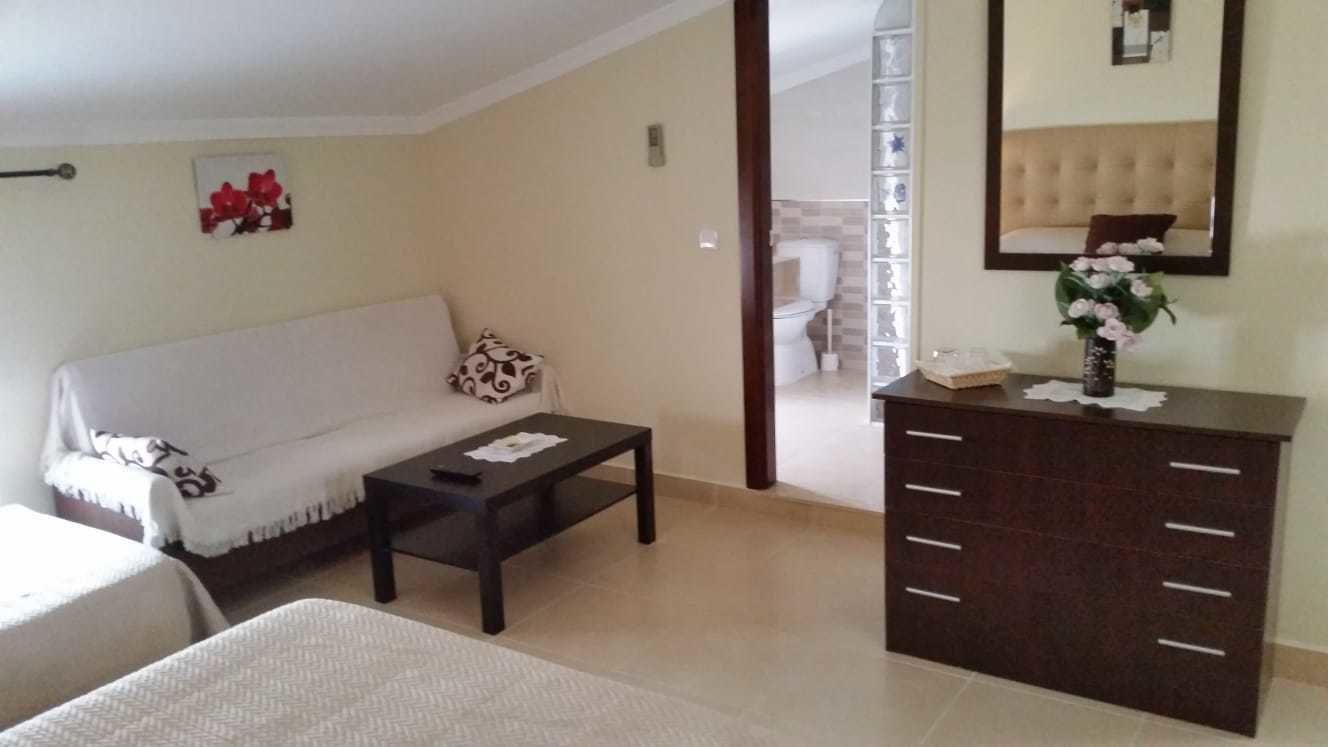 A living room with a sofa, a coffee table, a cabinet, and a mirror.