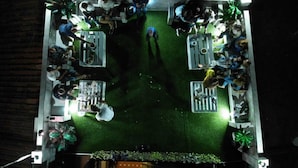 An outdoor dining area with tables and chairs arranged around a central grassy space. - Hostal Málaga (Arcos de la Frontera)