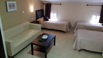 A hotel room with a single bed, a sofa, and a small table.