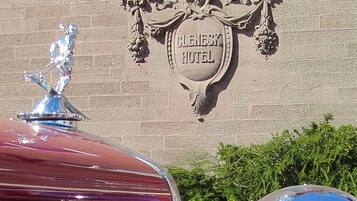 A sign for the Bluenesk Hotel with a decorative emblem and a car parked in front.