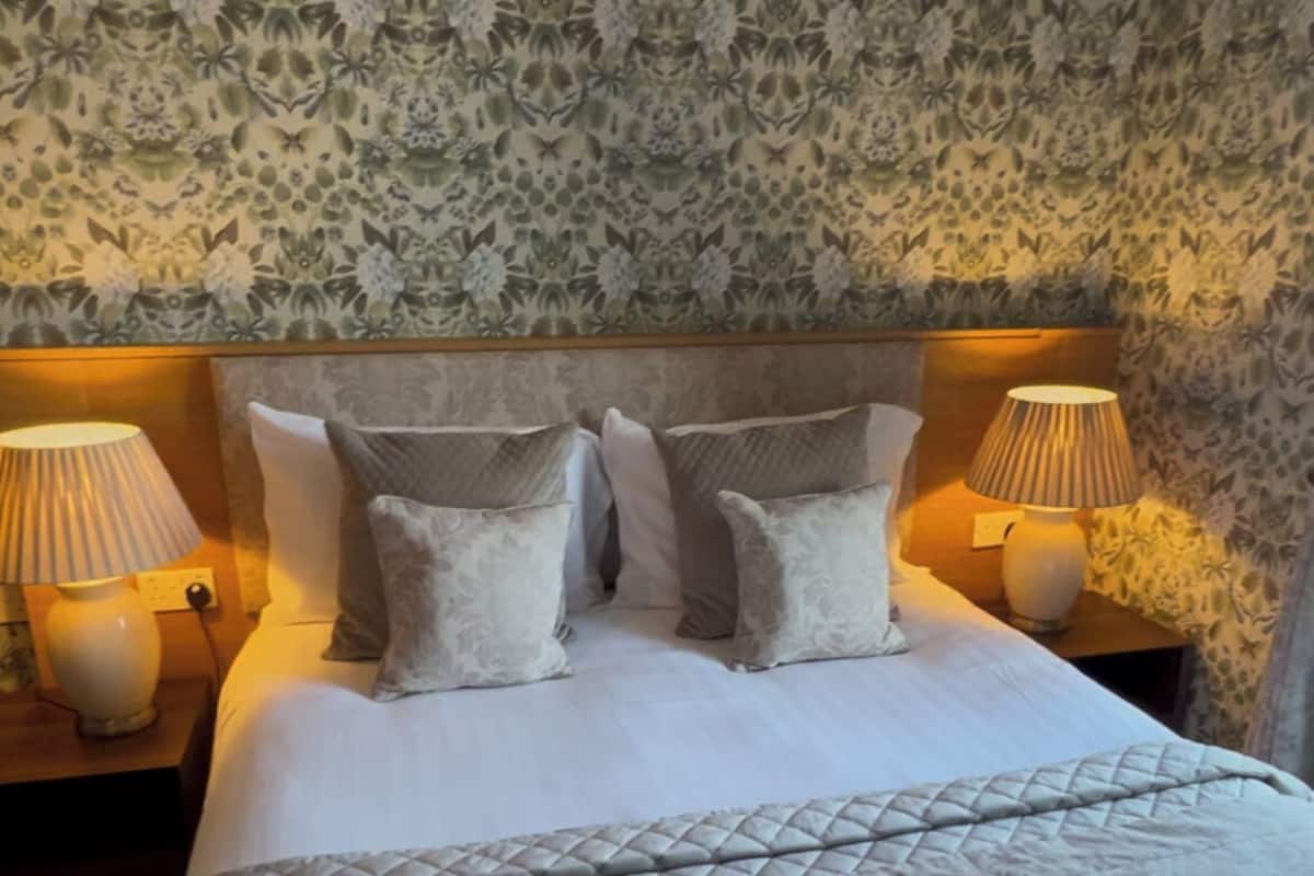A neatly made bed with a patterned bedspread and pillows, flanked by two bedside lamps on wooden nightstands.