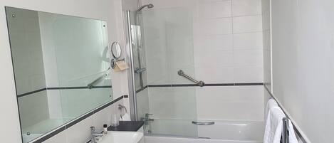 A bathroom with a glass shower enclosure, a sink, and a mirror.