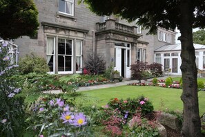 Un edificio histórico con un jardín bien cuidado al frente.