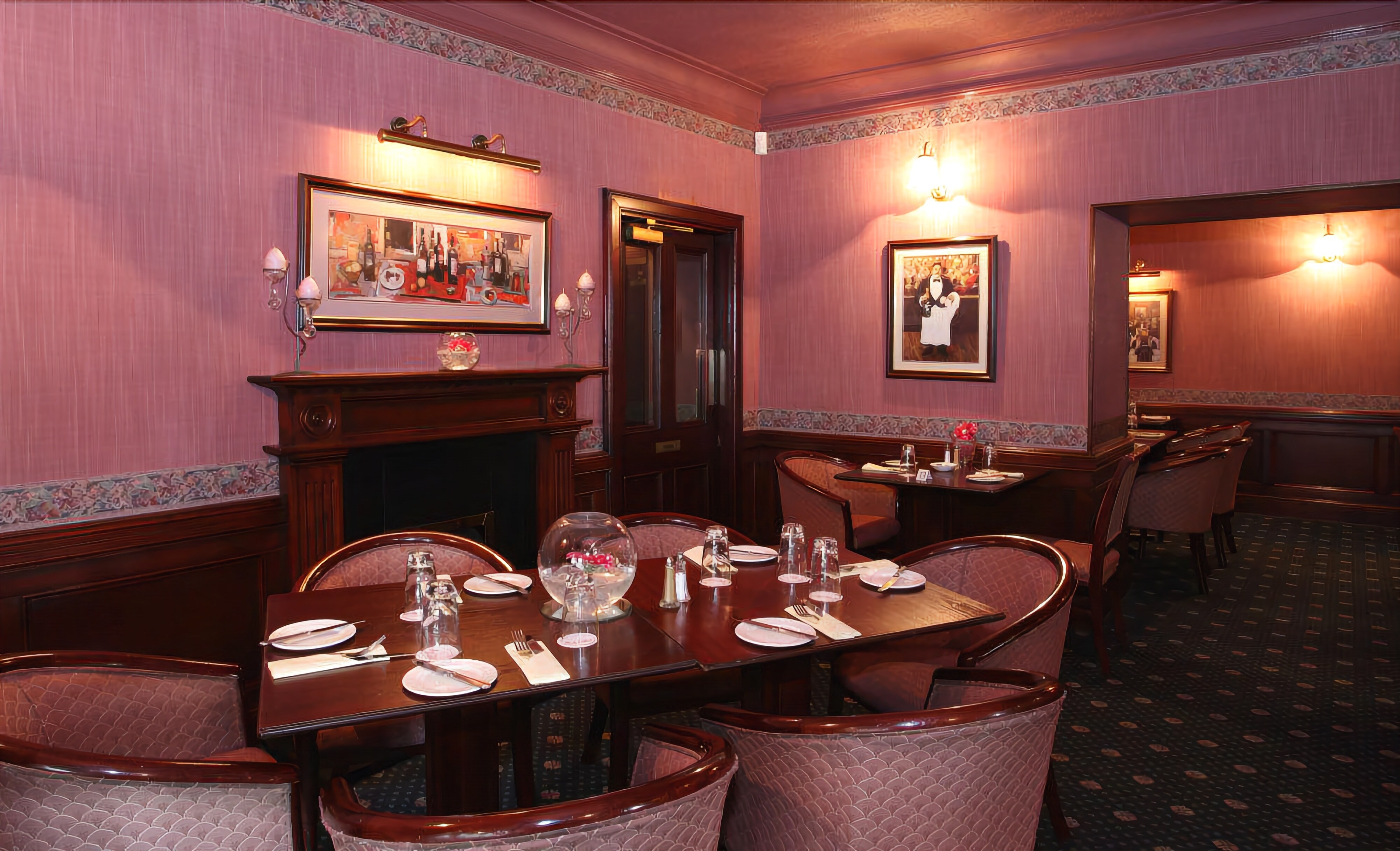 A formal dining room with a long table set for six, flanked by chairs, and a fireplace.
