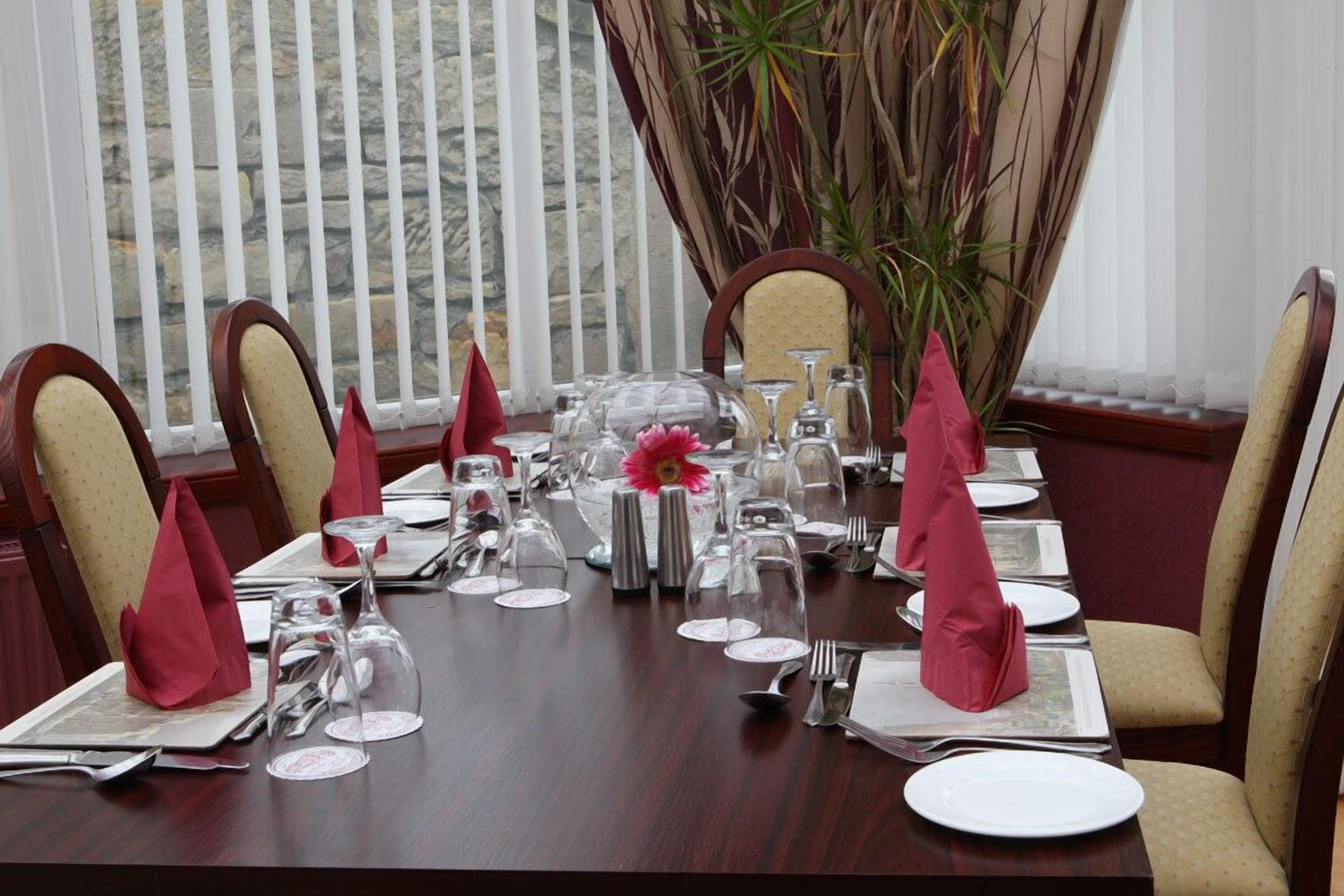 A dining table set for a formal meal with red napkins, silverware, and glassware.