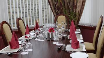 A dining table set for a formal meal with red napkins, silverware, and glassware.