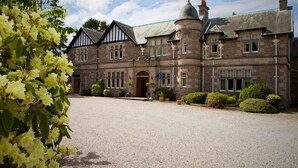 A large, historic stone building with a symmetrical facade, multiple windows, and a prominent turret. - Ramnee (Forres)