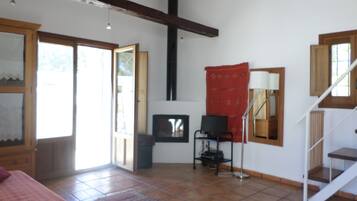A room with a bed, a desk, a chair, a lamp, a red tapestry, and a staircase.