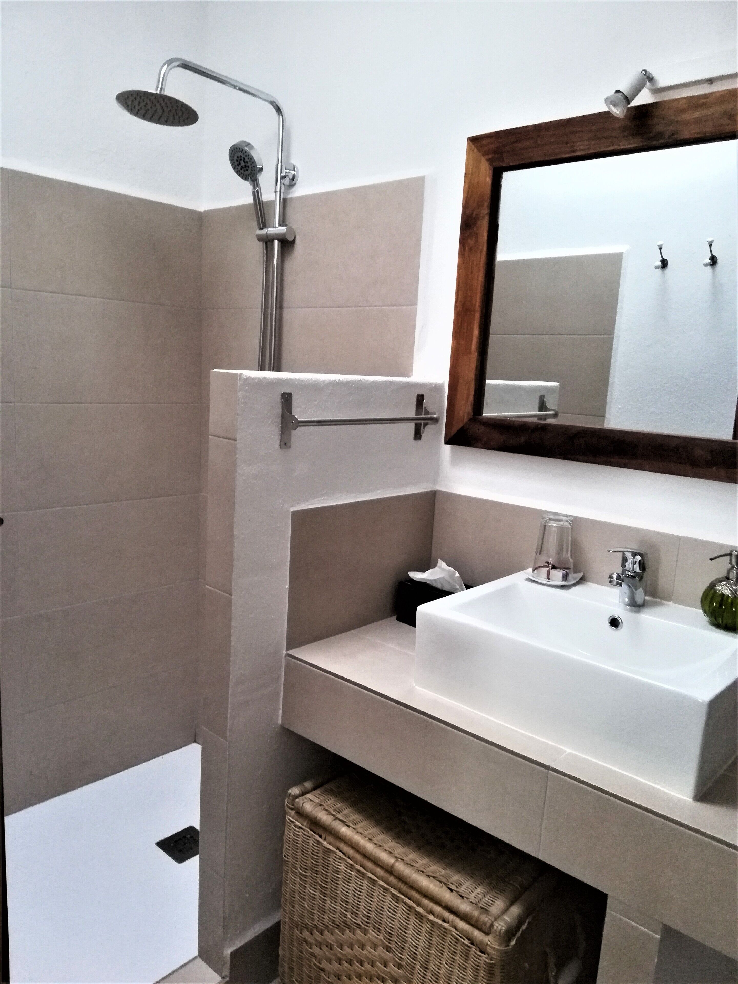 Un baño moderno con ducha, lavamanos y espejo.